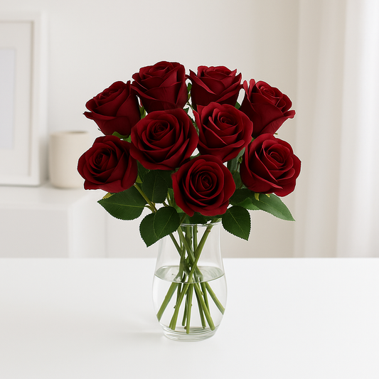 Ein realistischer Strauß aus zwölf dunkelroten künstlichen Rosen in einer klaren Glasvase auf weißem Tisch, vor hellem und minimalistischem Hintergrund.