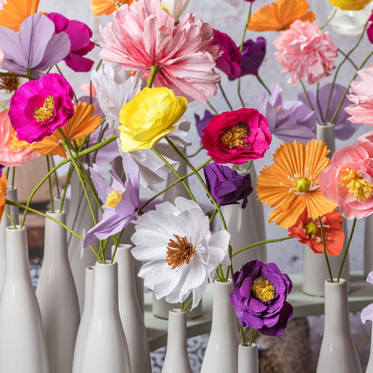 Bunte Papierblumen aus Krepppapier in weißen Vasen – handgefertigte Dekoblumen in leuchtenden Farben.