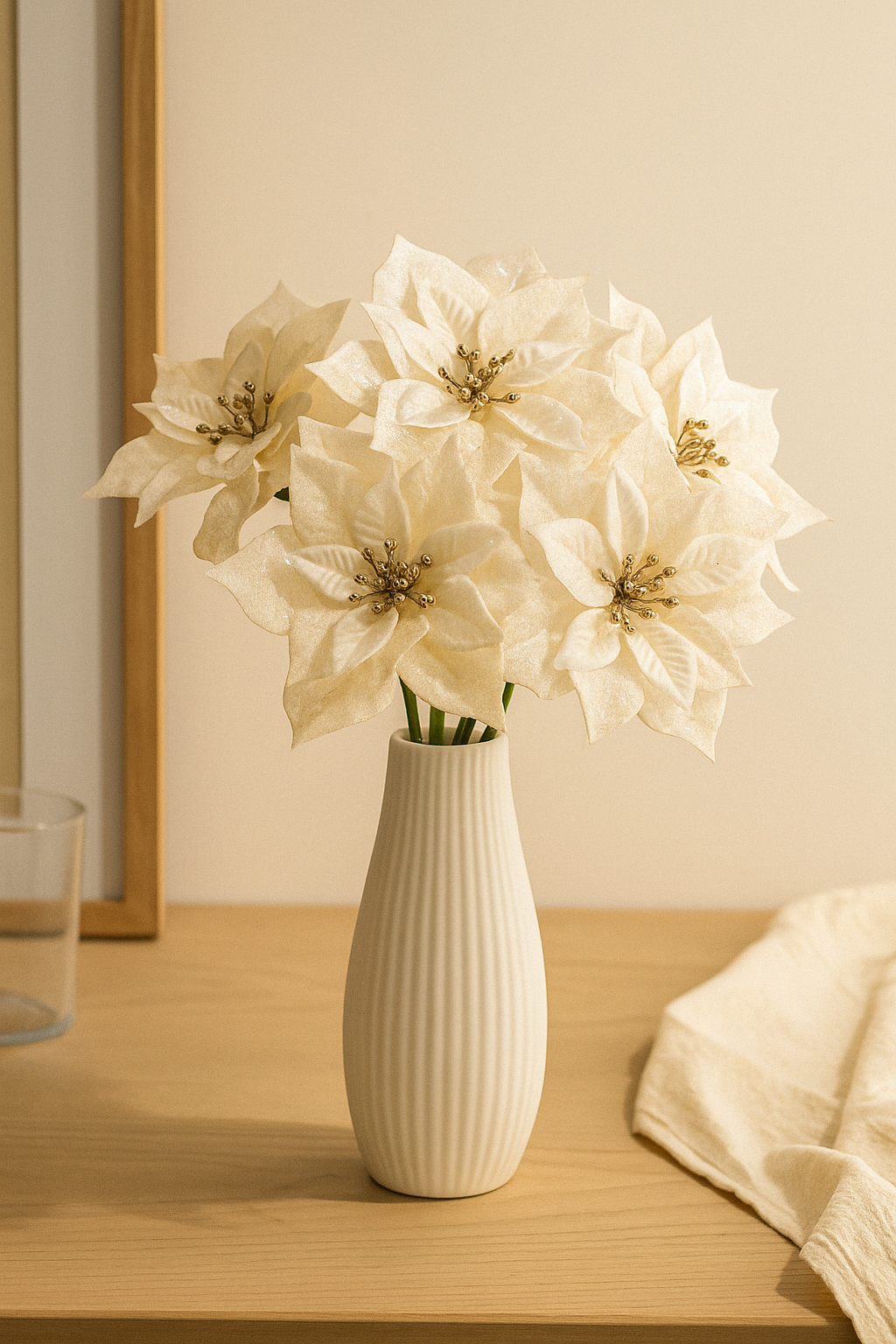 Künstliche cremefarbene Weihnachtssterne als Strauß in eleganter weißer Vase auf Holztisch – realistische Poinsetta mit goldenen Akzenten für stilvolle Winterdekoration