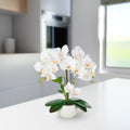 Weiße künstliche Orchidee in glänzendem Keramiktopf auf Holzregal