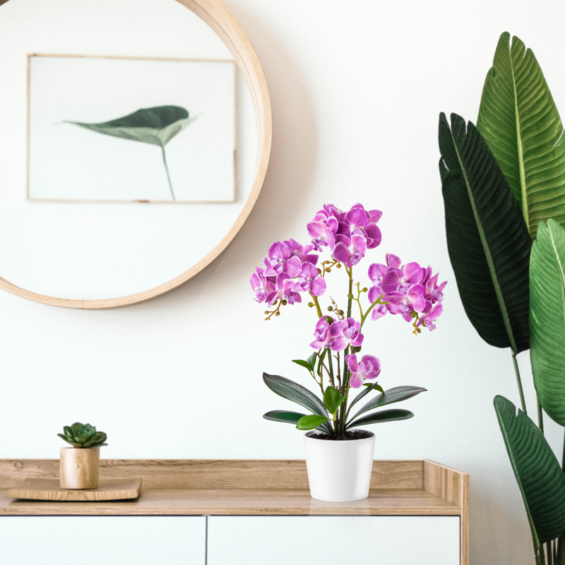Rosa Deko-Orchidee als künstliche Topfpflanze auf Sideboard